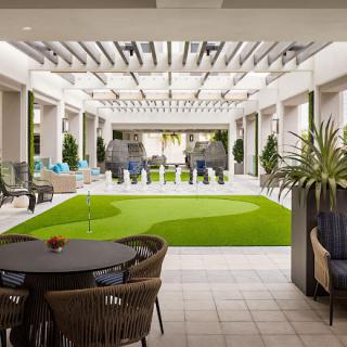 A modern indoor lounge area with seating and greenery, featuring artificial grass and stylish decor.