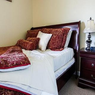 A neatly made bed with decorative pillows and a nightstand with a lamp in a cozy bedroom.