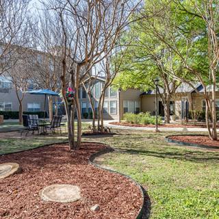 A well-maintained garden area in an apartment complex with trees and seating.