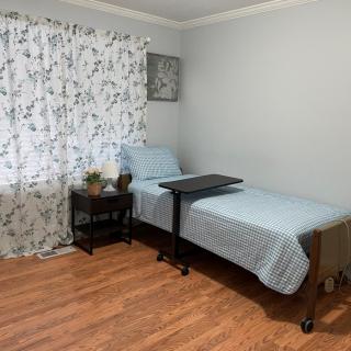 A cozy bedroom with a single bed, nightstand, and floral curtains.