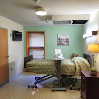 A comfortable hospital patient room with a bed, bedside table, and window.