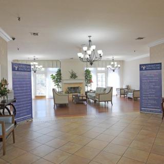 A spacious lobby with elegant decor, featuring a seating area near a fireplace and chandeliers overhead.
