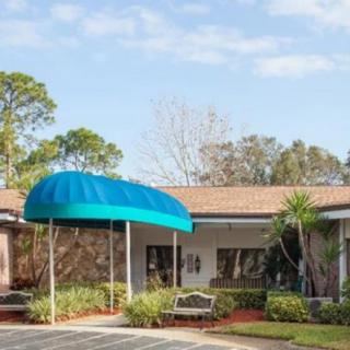A building entrance with a blue awning and landscaped surroundings.