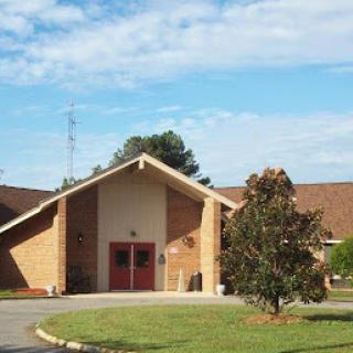 A serene view of a church building surrounded by greenery under a partly cloudy sky.