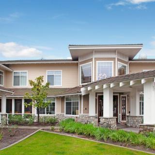A modern residential house with a spacious garden under a clear blue sky.