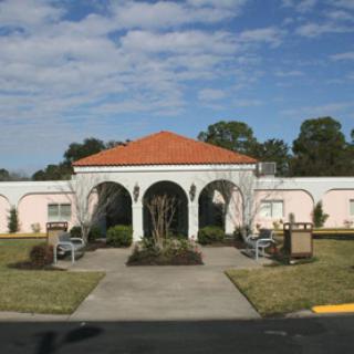 A charming building featuring arches and a tiled roof, surrounded by greenery under a clear blue sky.