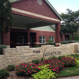 A residential building entrance with a landscaped garden and sign.