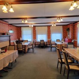 A cozy restaurant interior featuring neatly arranged tables and chairs, with soft lighting and brick walls.