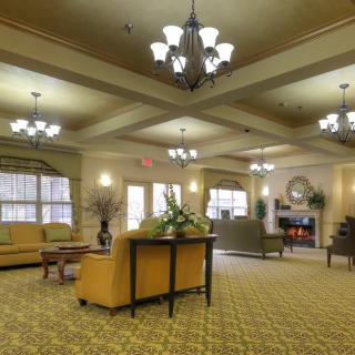 A spacious and elegantly decorated lobby featuring comfortable seating, chandeliers, and a cozy fireplace.