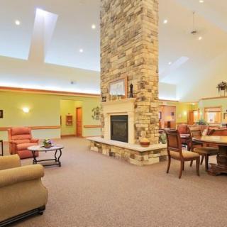 A spacious living room with a central stone fireplace and comfortable seating.