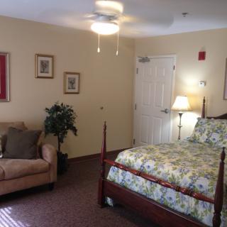 A cozy bedroom with a floral-patterned bed, a beige sofa, and warm lighting.