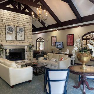 A cozy living room with a stone fireplace, elegant chandelier, and comfortable seating.