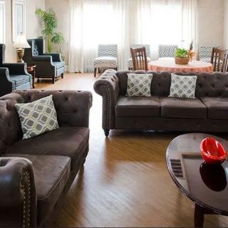 A cozy living room featuring dark sofas with patterned cushions, a round coffee table, and ample seating.