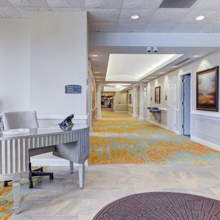 A spacious lobby area with a desk, artwork, and carpeted hallway.