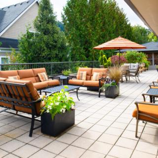 A spacious patio with comfortable seating and an outdoor umbrella, surrounded by greenery.