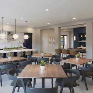 A modern dining area with wooden tables and chairs, featuring stylish lighting fixtures and an open kitchen layout in the background.