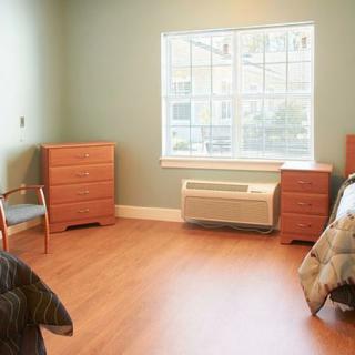 A simple bedroom with wooden furniture and a large window.