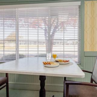 A cozy dining area with a table set for breakfast near a window with blinds.