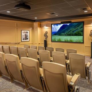 A cozy home theater with multiple rows of seating and a large screen.