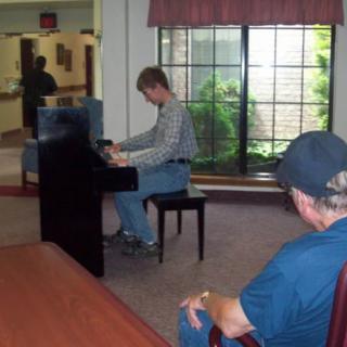 A person plays the piano in front of an audience indoors.