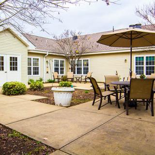 A cozy backyard patio with seating and an umbrella, adjacent to a house.