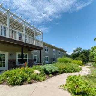 A modern building with a garden pathway and lush greenery under a clear blue sky.