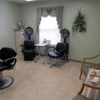 A cozy salon interior featuring styling chairs, hair dryers, and a small waiting area.