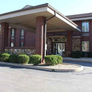 A hotel entrance with a covered driveway and surrounding greenery.