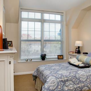 A cozy bedroom with a large window, patterned bedspread, and soft lighting.