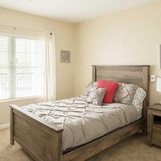 A cozy bedroom featuring a wooden bed with patterned bedding and accent pillows, next to a window.