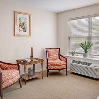 A cozy living room with two armchairs, a small table, and a window letting in natural light.
