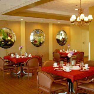 Elegant dining area with tables set for guests, featuring chandeliers and decorative mirrors.
