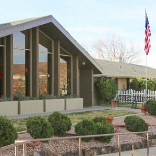 A mid-century modern house with large windows, an American flag, and neatly landscaped yard.