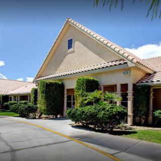 A suburban house with a gabled roof surrounded by greenery on a sunny day.