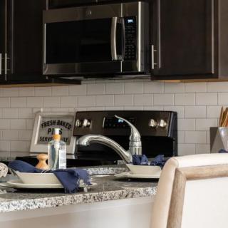 A modern kitchen with a countertop featuring a sink, dishes, and dark cabinetry.