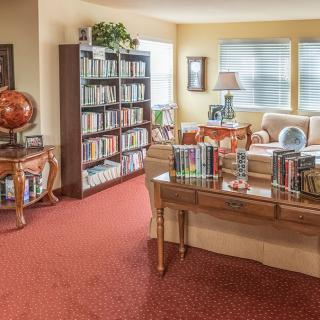 A cozy living room library with bookshelves, comfortable seating, and a globe.