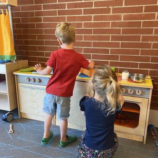 Children playing with a toy kitchen set indoors.