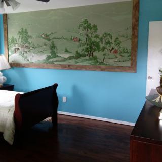 A cozy bedroom featuring a large wall mural and wooden furniture.