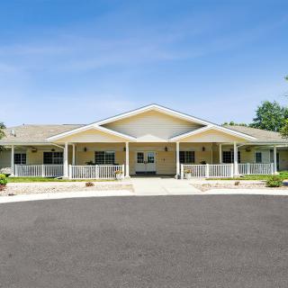 A spacious residential building with a large driveway and covered porches.