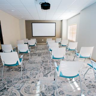 An empty conference room with chairs arranged facing a projection screen.