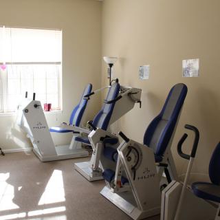 A small gym room with several exercise machines lined up against the wall.