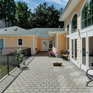A spacious outdoor patio area next to a building, featuring potted plants and surrounded by tall trees.