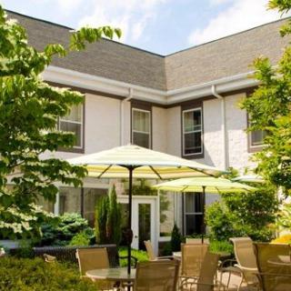 A peaceful patio space with seating and umbrellas surrounded by lush greenery.