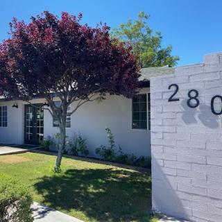 A residential house with a well-maintained lawn and prominent address numbers displayed on a wall.