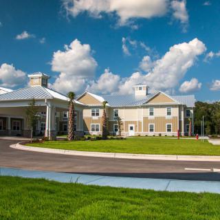 A modern building surrounded by lush green grass under a blue sky with clouds.