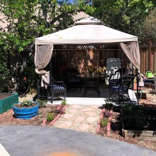 A cozy outdoor gazebo surrounded by lush greenery and comfortable seating.