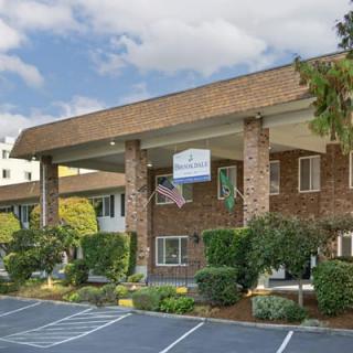 A two-story hotel building with a large entrance and parking area.