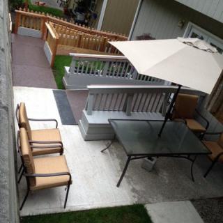 A cozy patio with outdoor furniture, including a table, chairs, and a large umbrella.