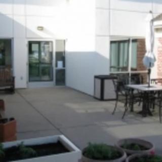 A patio area with tables, chairs, and planters outside a building.