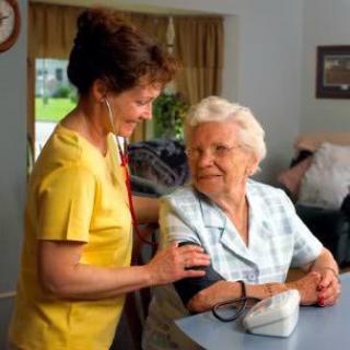 A nurse checking the blood pressure of a senior woman during a home visit.